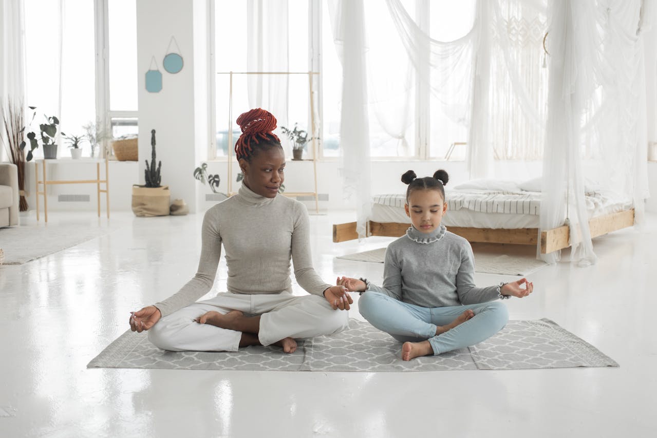 Two women seated on a yoga mat in a serene room