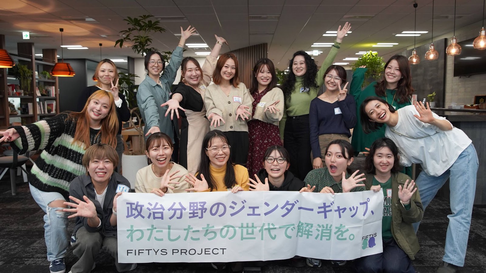 FIFTYS PROJECTのメンバーの集合写真。「政治分野のジェンダーギャップ、わたしたちの世代で解消を」と書かれたバナーを持っている。