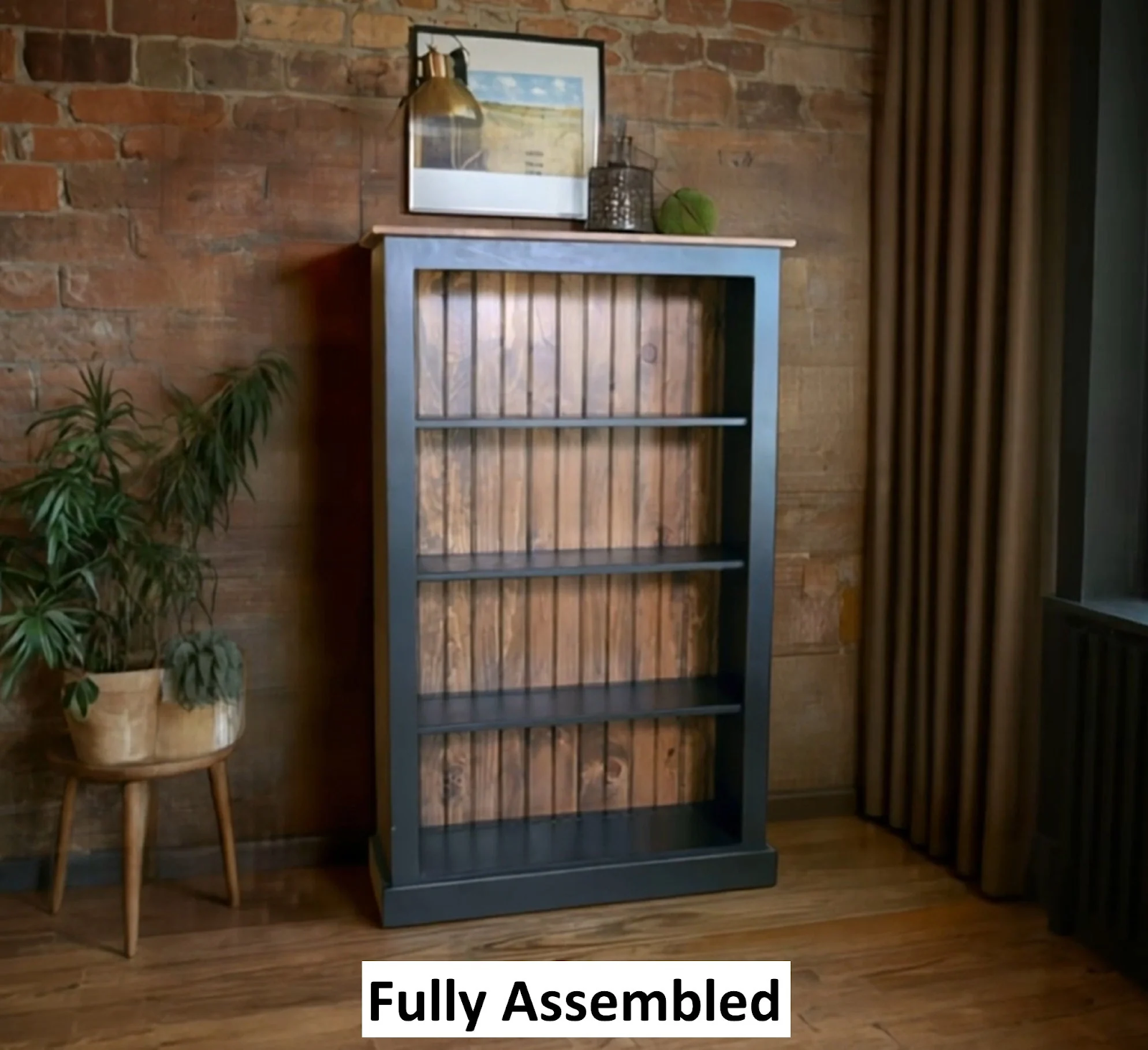 US handmade wooden bookshelf, painted navy blue with rustic wood paneled back, featuring four shelves against exposed brick wall, styled with plants and brass lamp, available at BetterCrafter.com