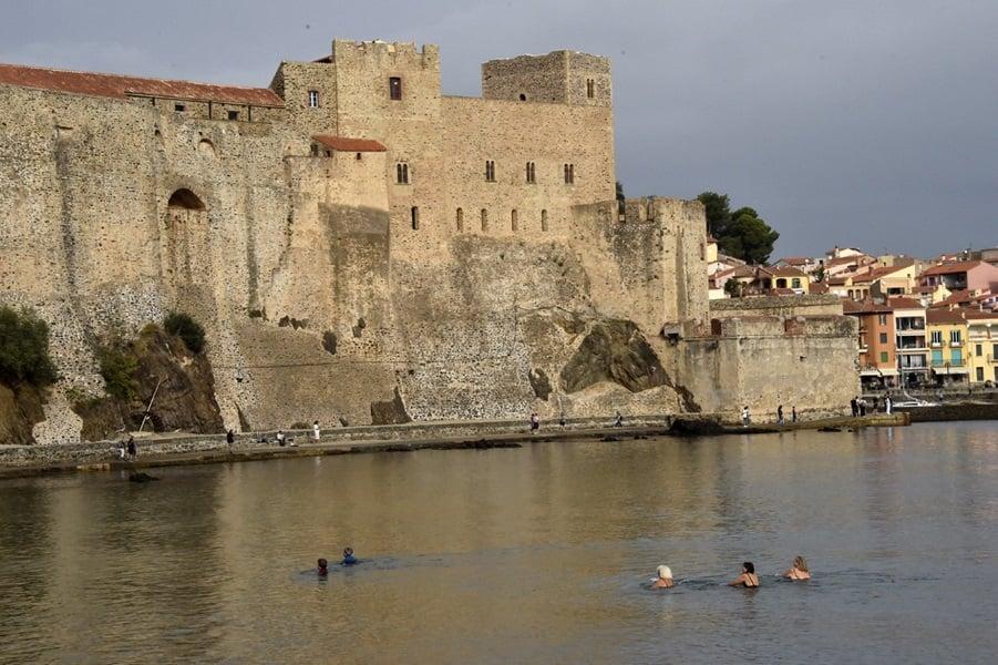 A group of people swimming in the water with Bodiam Castle in the background

Description automatically generated