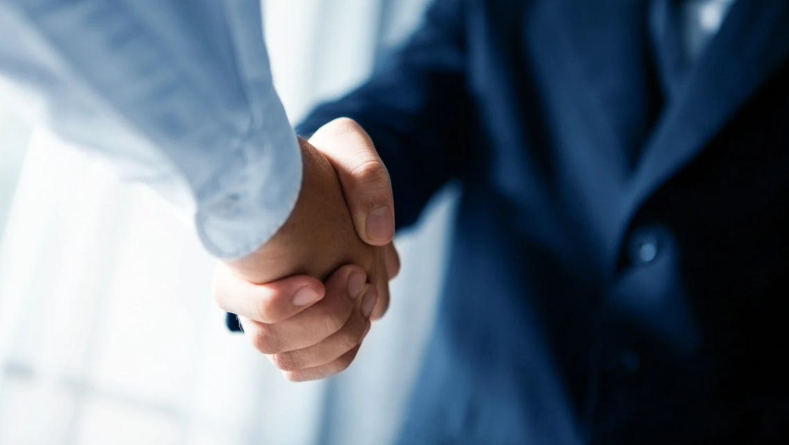 (Close-up of a handshake between two professionals, symbolizing trust, legal representation, or reaching a settlement.)