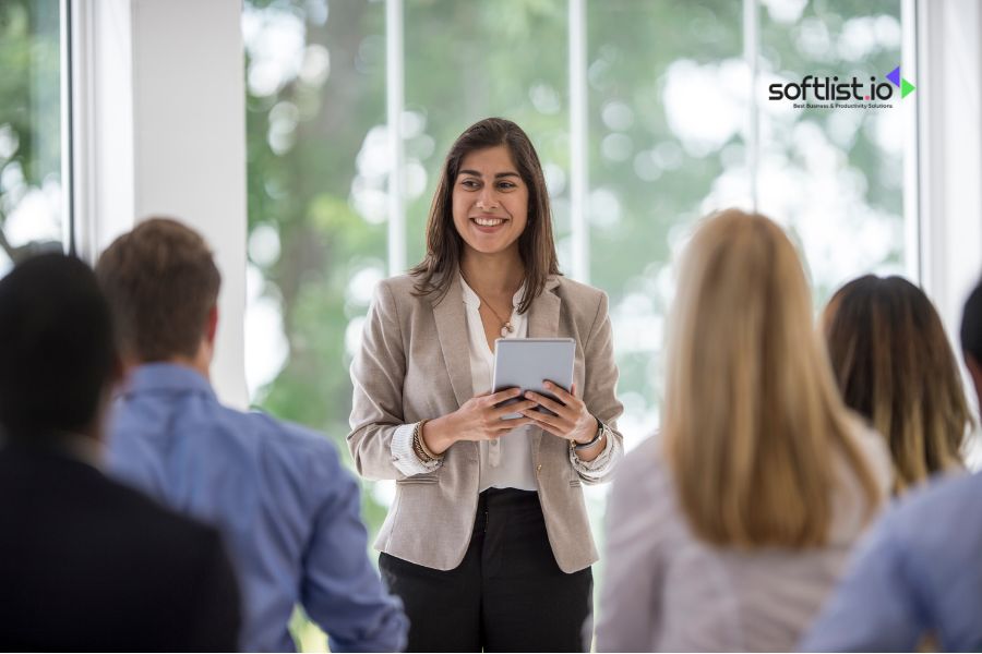 Smiling woman giving presentation to an audience, holding a tablet