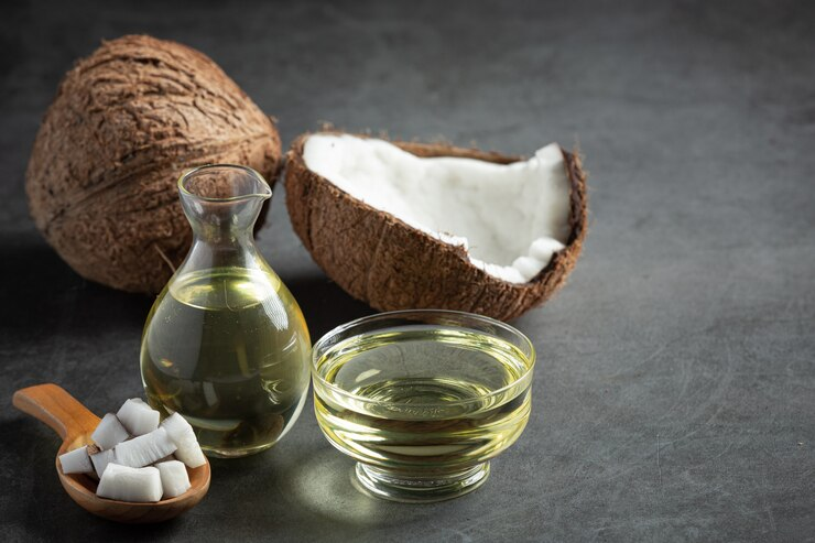 Jug of coconut oil with coconut on background