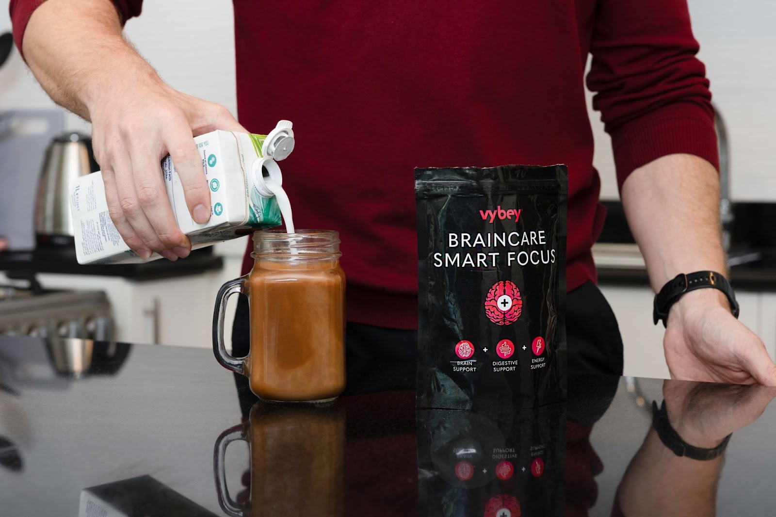 Man pouring milk into a cup of vybey Braincare Smart Focus, a coffee alternative designed to enhance brain health, focus, and mental clarity without the jitters or crashes of traditional coffee