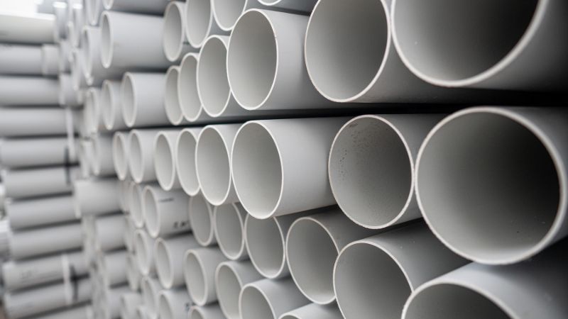 Horizontal rows of stacked gray PVC pipes.