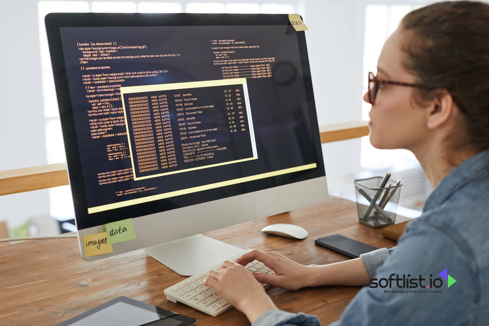 A woman working on code displayed on a large desktop monitor