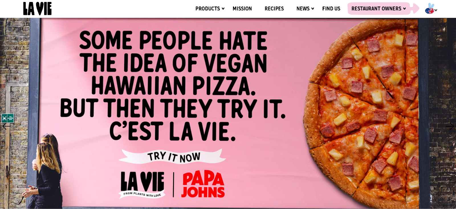 A screengrab of the first thing that comes up when you're on the La Vie website, it reads "some people hate the idea of vegan Hawaiian pizza. But then they try it. C'est la vie" - it's a partnership with La Vie and Papa Johns, and is a billboard of pizza and then the quote. 