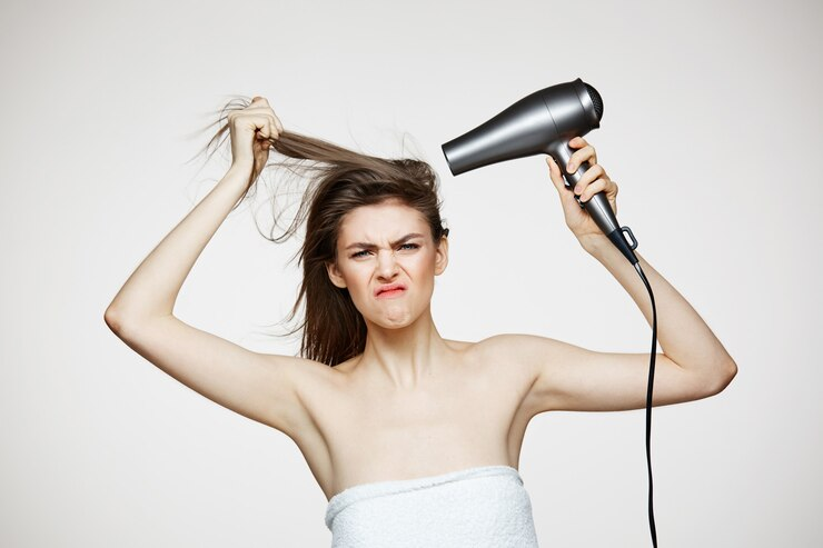 beautiful woman in towel with hair dryer making agitated face