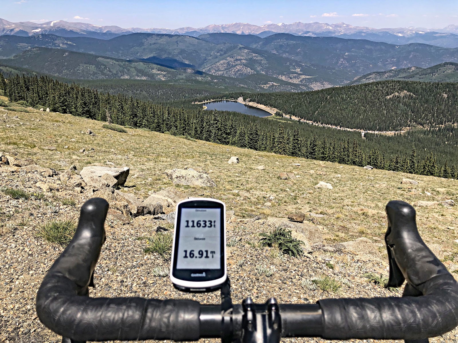 Cycling Mt. Evans, Colorado - bike handlebars and Garmin looking over hillside, above treeline, Garmin reads 11633 feet elevation 