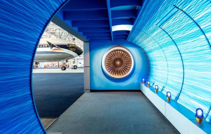 A decorated blue tunnel with a glimpse of an airplane beyond it.