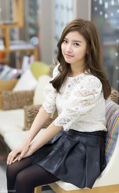 This contains an image of Kim So Eun sitting on top of a chair wearing a white shirt and black leather skirt