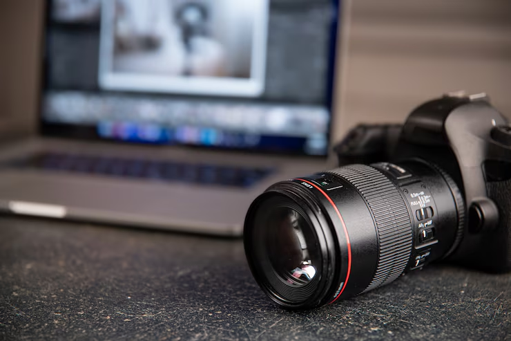 Professional camera beside an out-of-focus laptop