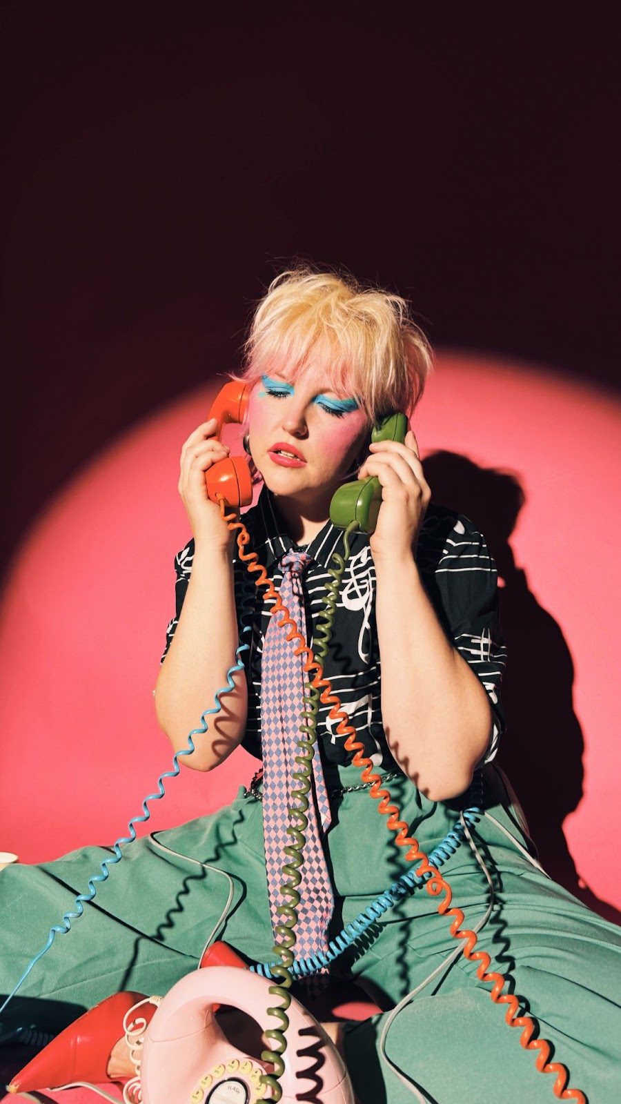 Caroline Kingsbury in full 80s attire and aesthetic with cord phones