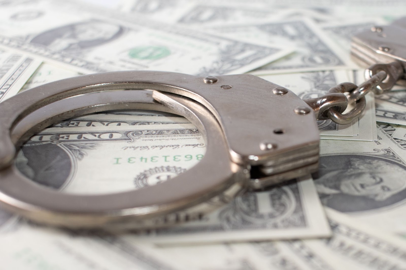 Handcuffs on money, representing financial crime consequences