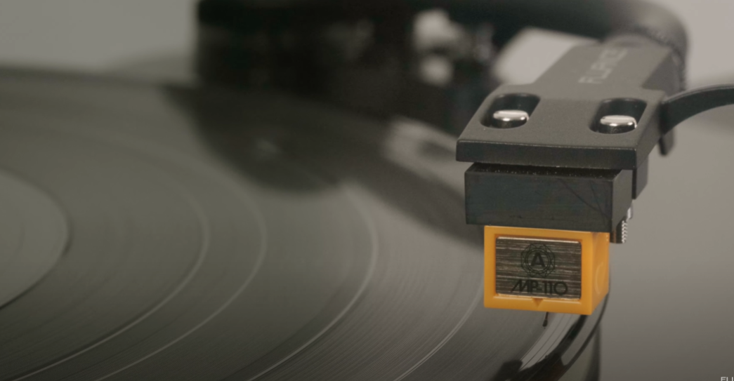 Close-up of a turntable stylus (cartridge) playing a vinyl record