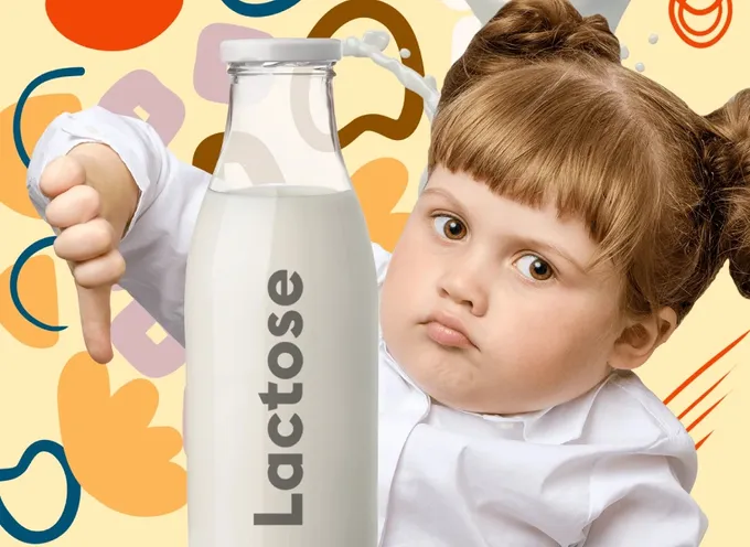 A young girl with pigtails joyfully holding a bottle of milk.