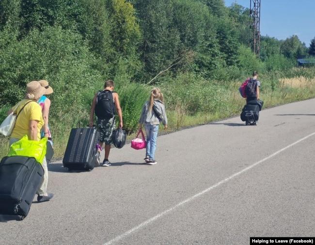 A group of people with luggage on a road

Description automatically generated