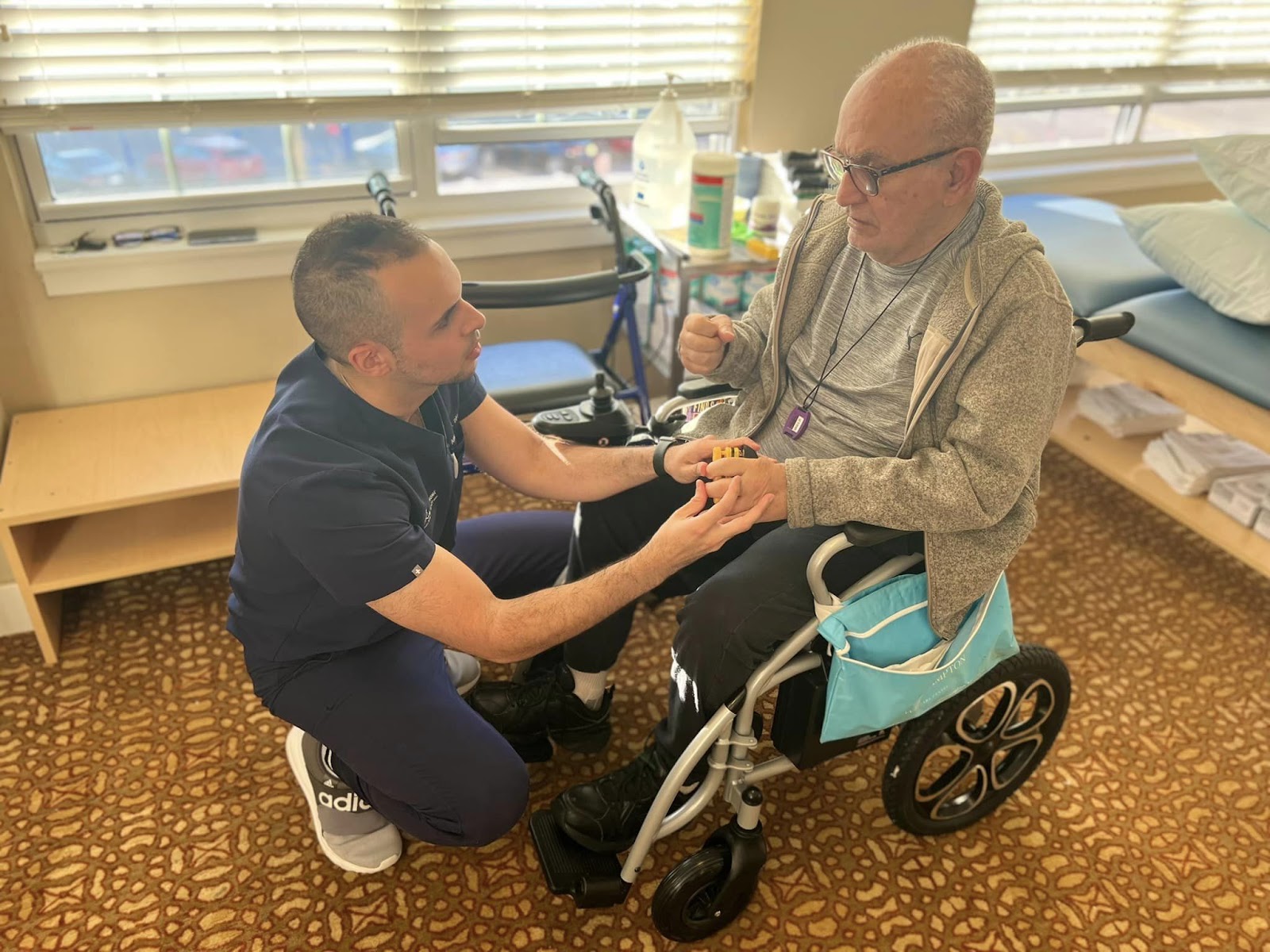 A physical therapist kneeling over and helping a man in a wheelchair