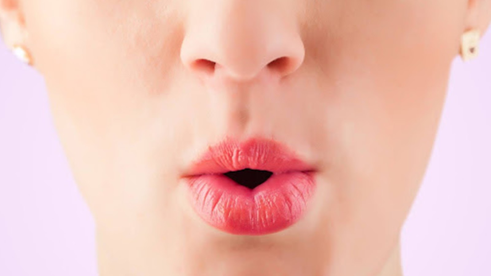 the mouth of a woman in an "o" shape in front of light purple background