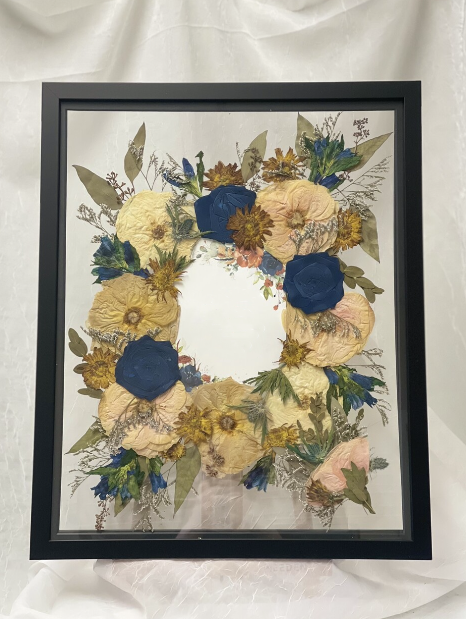 a wedding invitation designed inside a frame with a preserved bouquet