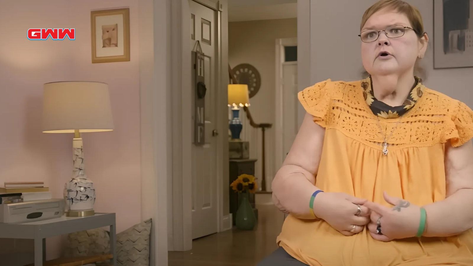 Tammy in orange top speaking, sitting in a cozy living room.