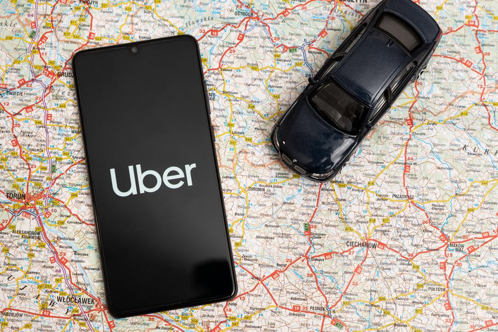 celular aberto no app da uber e miniatura de carro ao lado