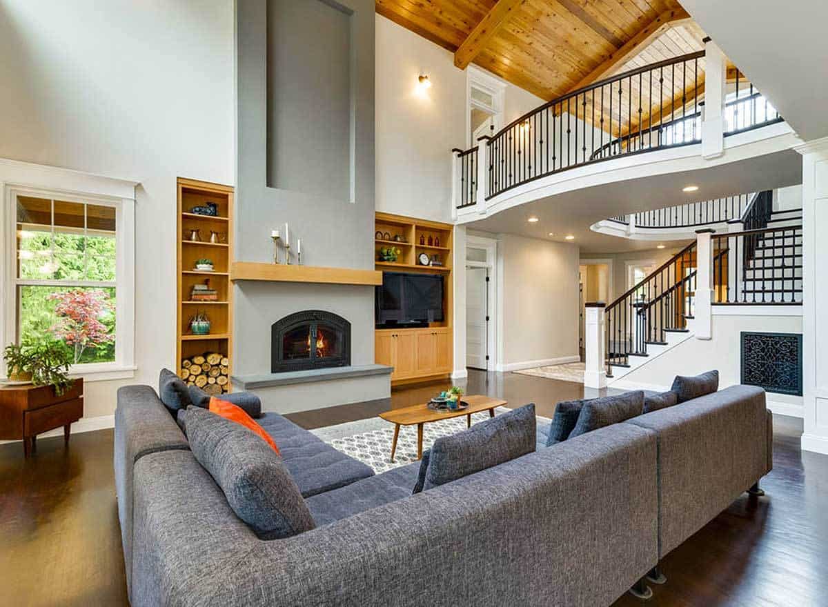 Living room with an L-shaped sofa and a fireplace flanked by wooden built-ins.
