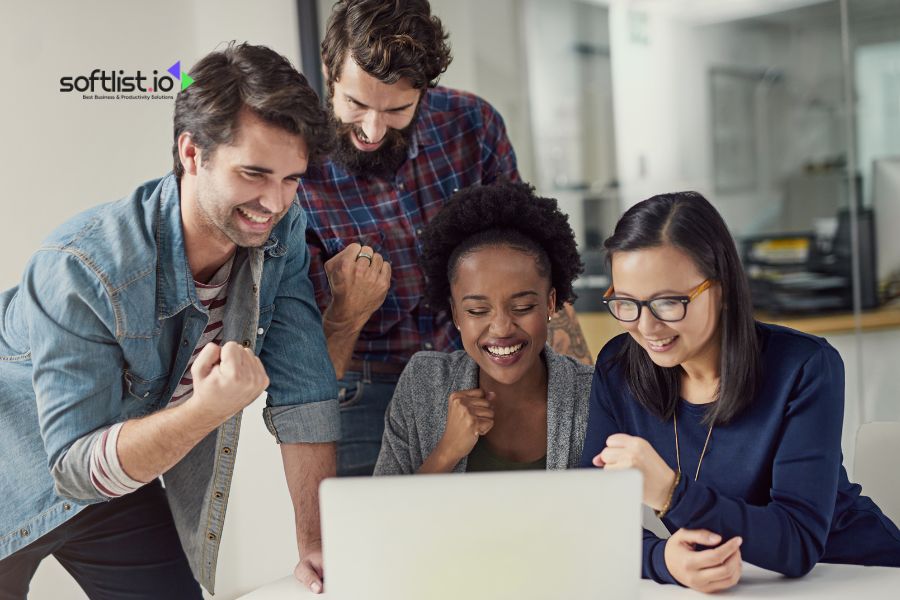 Group of colleagues celebrating a success while looking at a laptop.