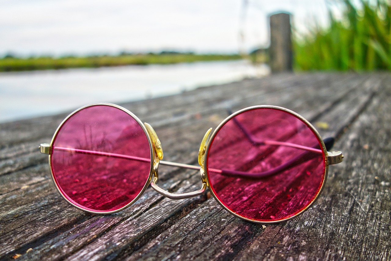 A pair of pink retro glasses with a wooden background. 