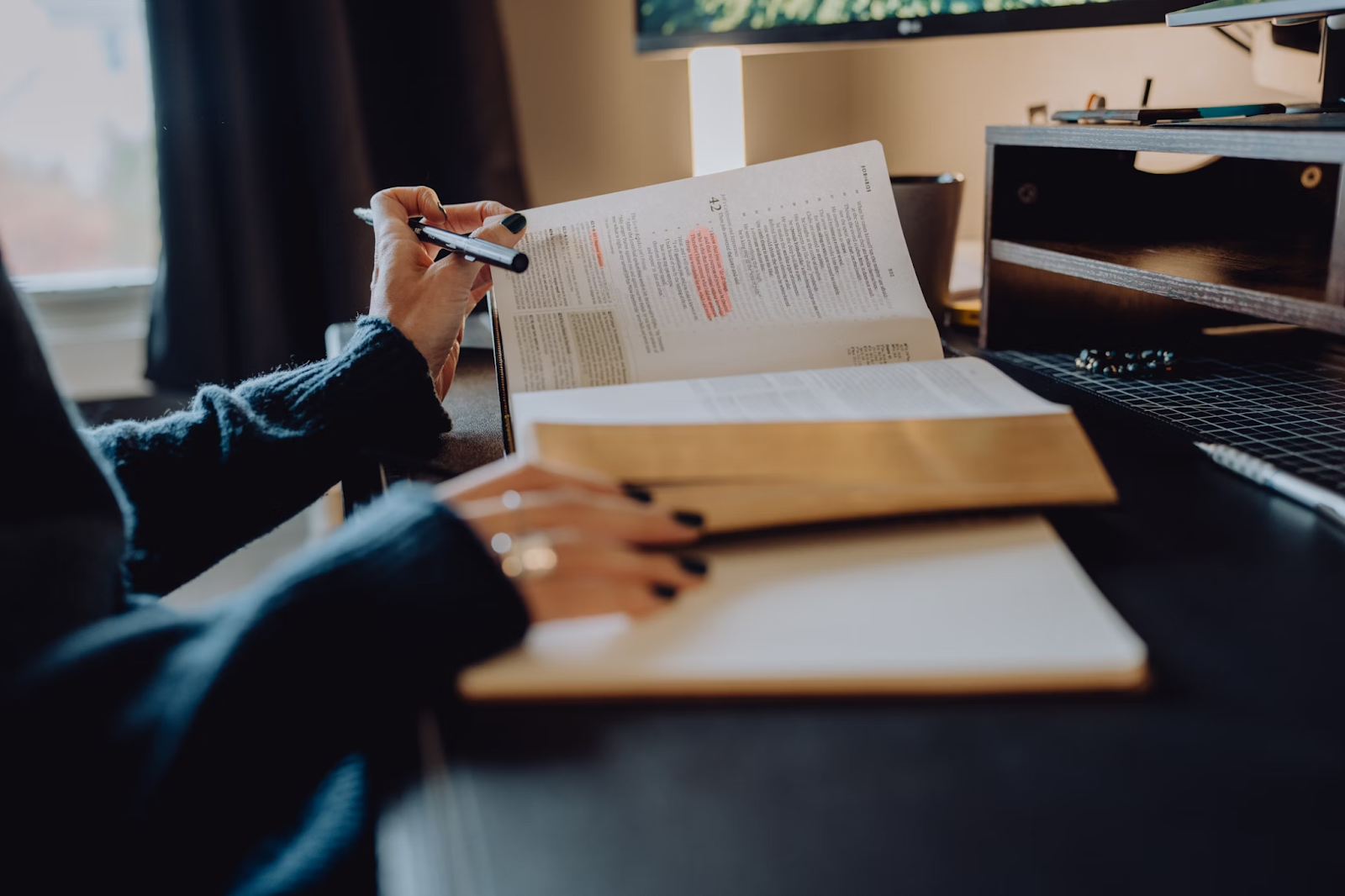 A woman scans through a research book highlighting relevant paragraphs to help her when writing essays for top grades.