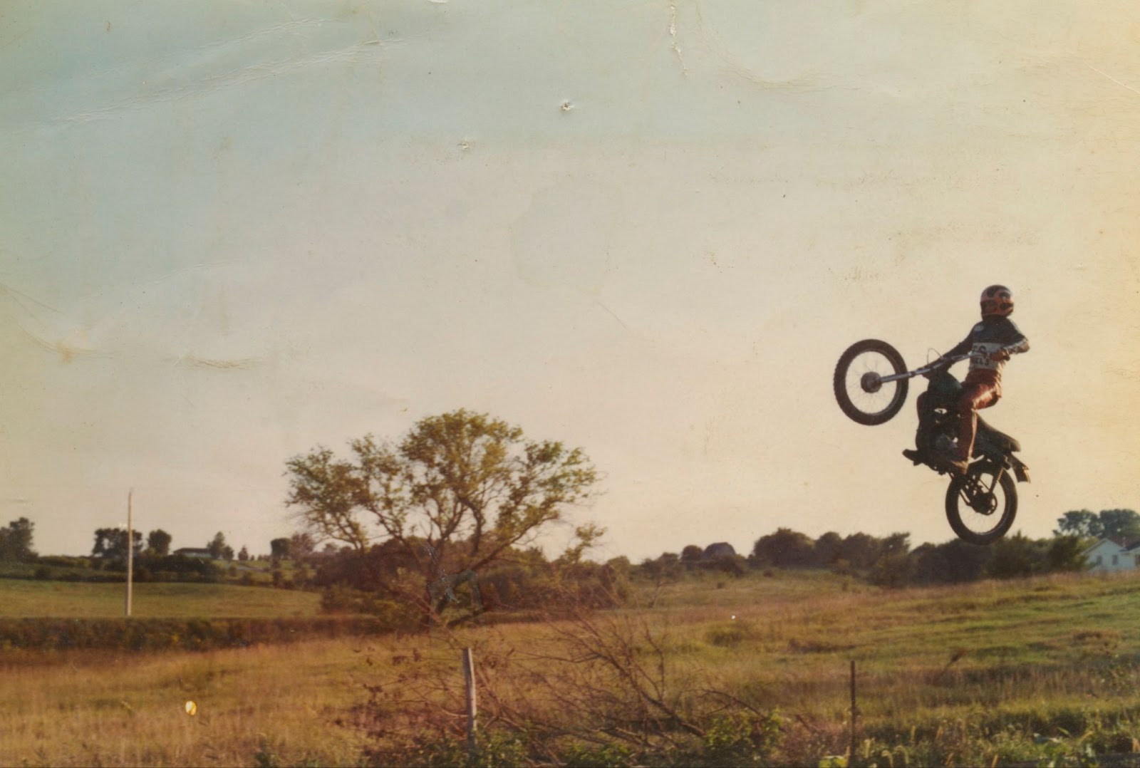 A man riding a motorcycle goes up on the back wheel on the right side of the image. 
