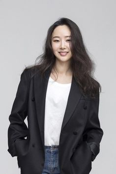 This contains an image of Min Hee Jin on a black suit putting her hand in her pocket