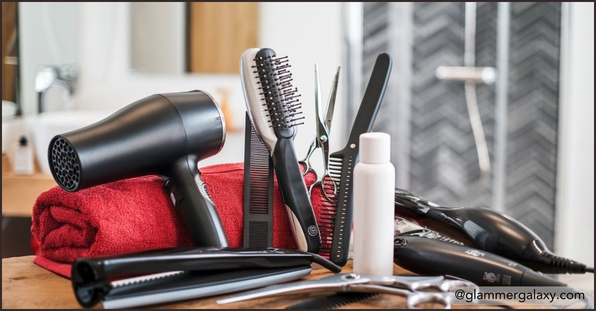 Hair styling tools on a wooden surface, including a dryer, brushes, and flat iron.