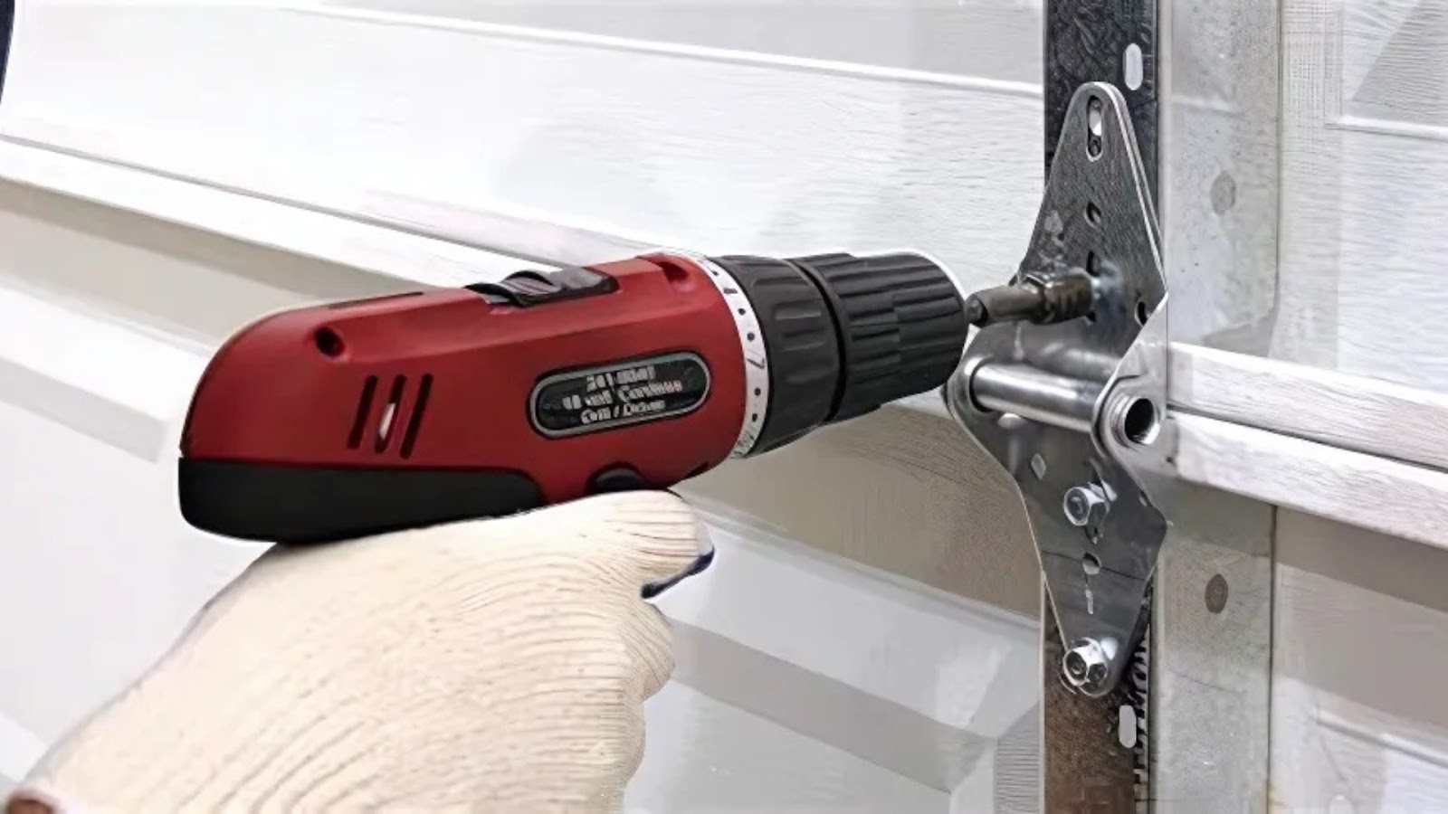 A man is using a drill to tighten loose hardware and fix a squeaky garage door hinge.