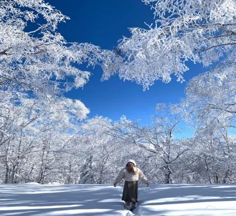 A person standing in a snowy forest  Description automatically generated