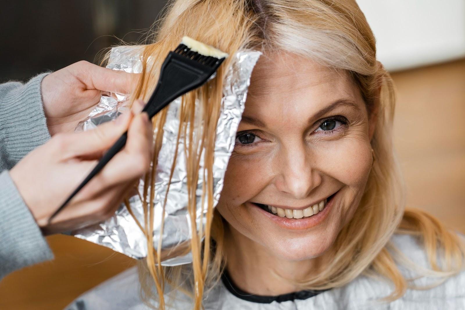 Smiling woman getting partial foil highlights done