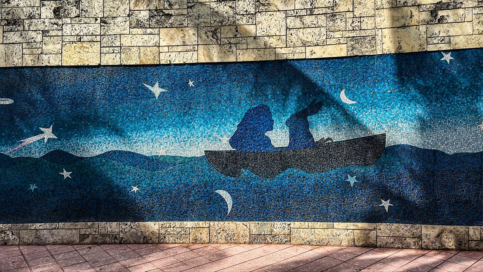 Colorful mosaic mural in Miami's Art District featuring the silhouette of a girl and a rabbit in a boat against a blue, star-filled night sky with crescent moons and shooting stars.