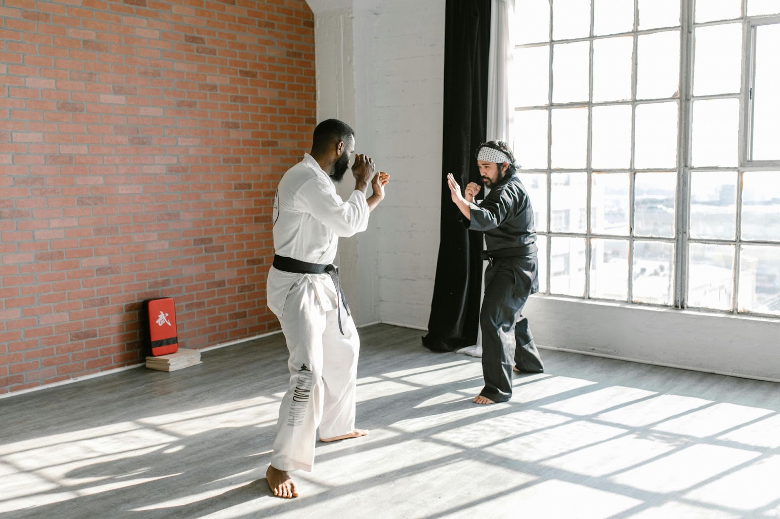 Two martial arts instructors stand facing each other in a ready stance during a training session