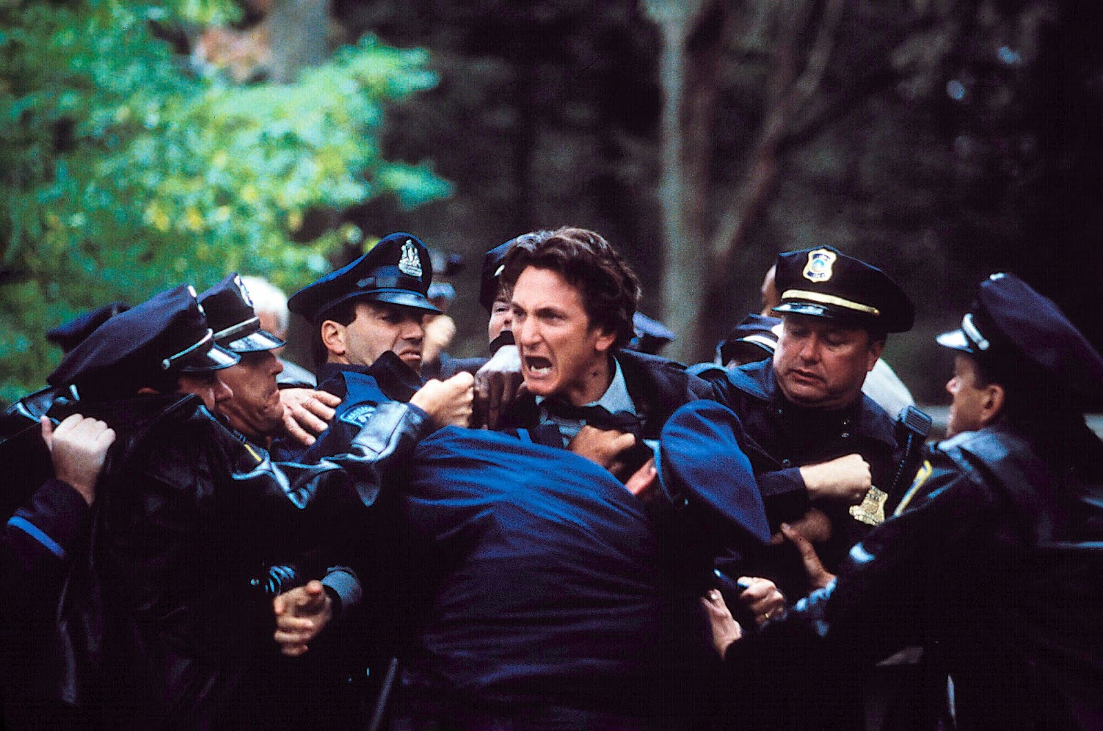 Sean Penn, interpretando un personaje en crisis emocional, forcejeando con varios policías durante una intensa escena de arresto en 'Mystic River'.