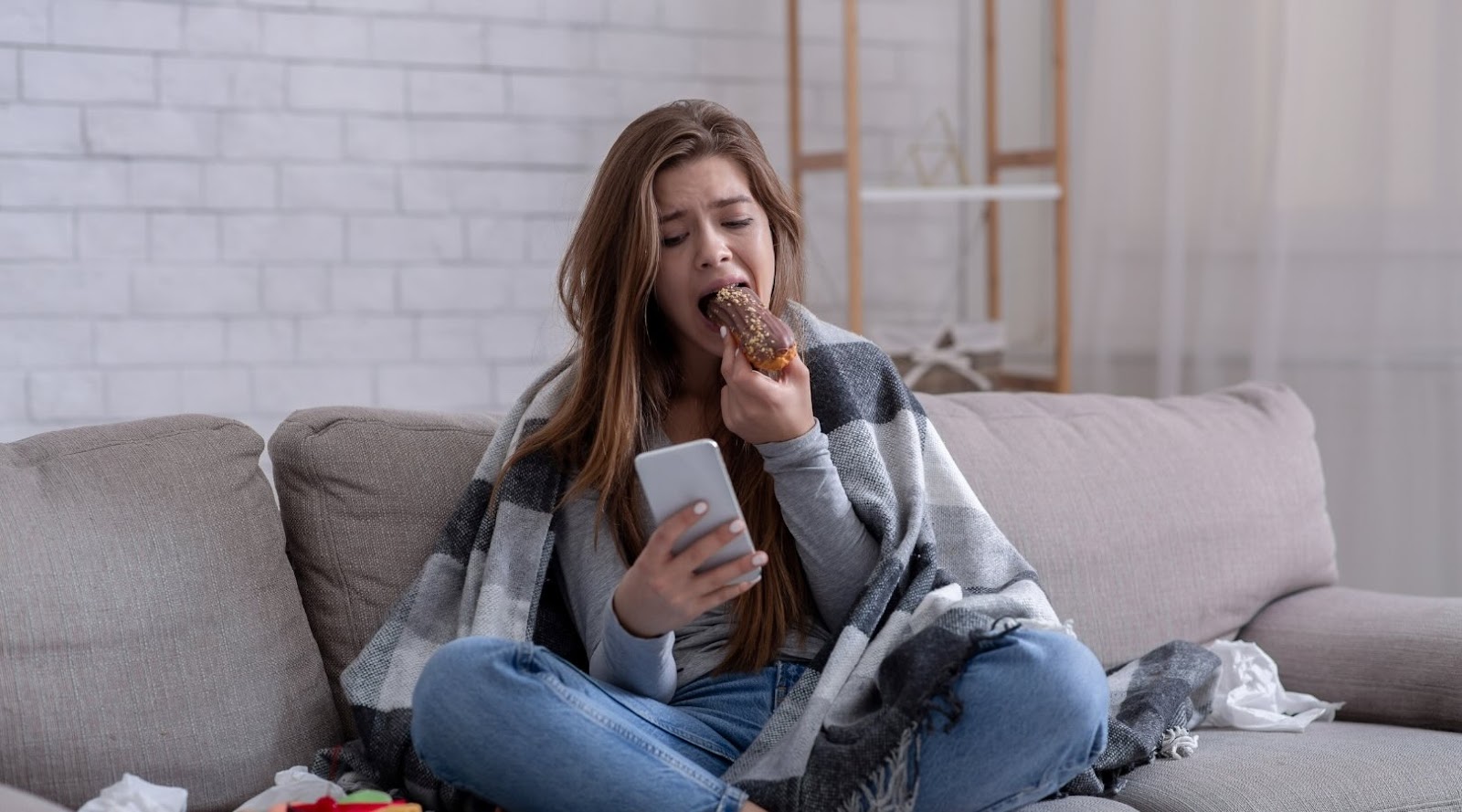 Young woman upset with sweet pastry looking at her smartphone