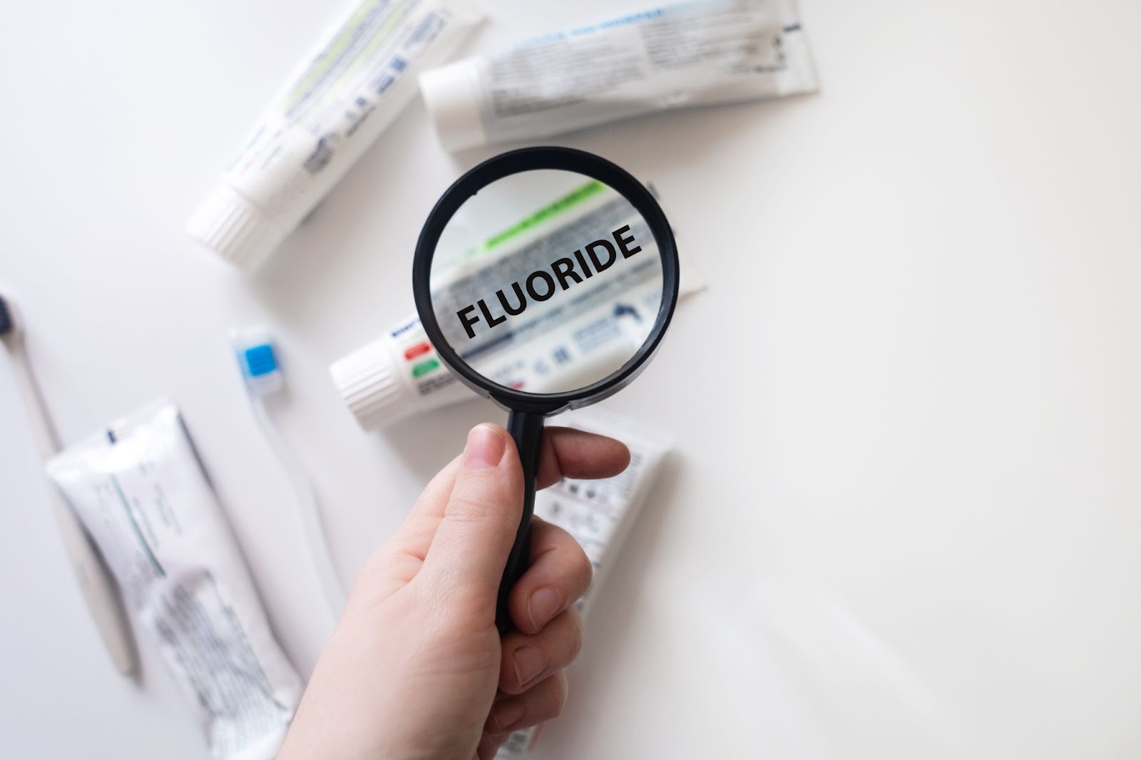 A person examines the ingredients list on a tube of toothpaste, highlighting fluoride.