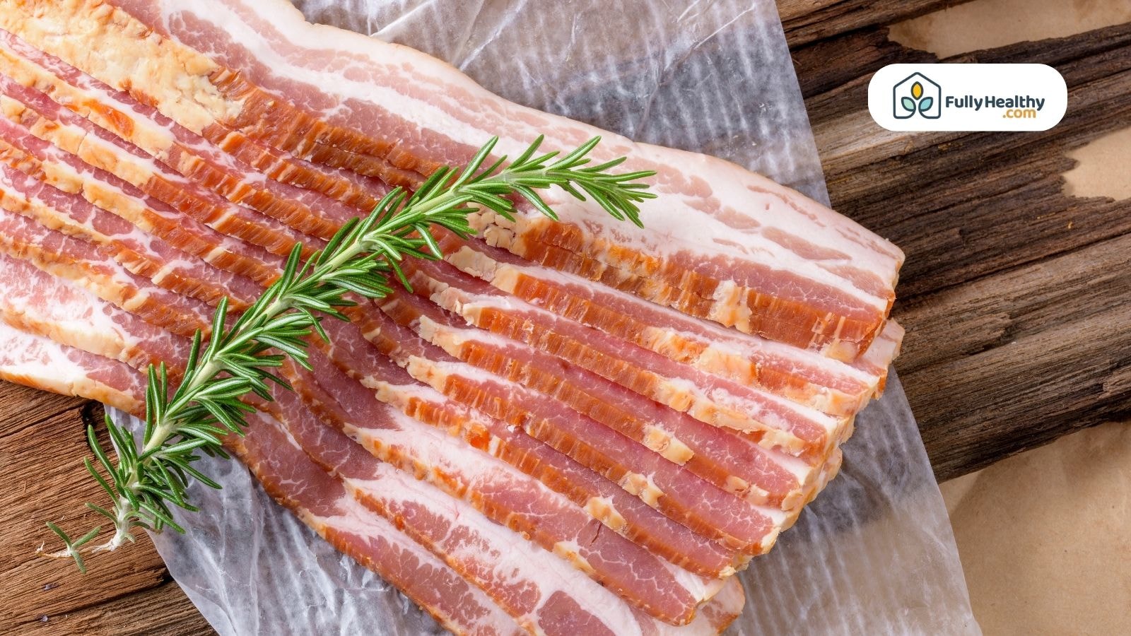 Uncooked pork bacon slices with rosemary on rustic wooden surface