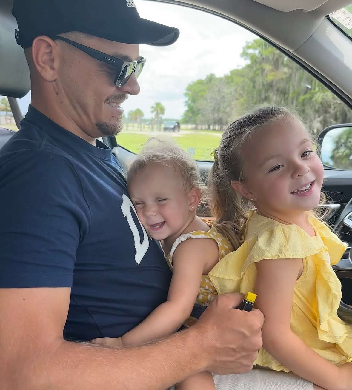 Dad with two daughters in his lap smiling as they cruise through the Wild Florida Drive-thru Safari Park.
