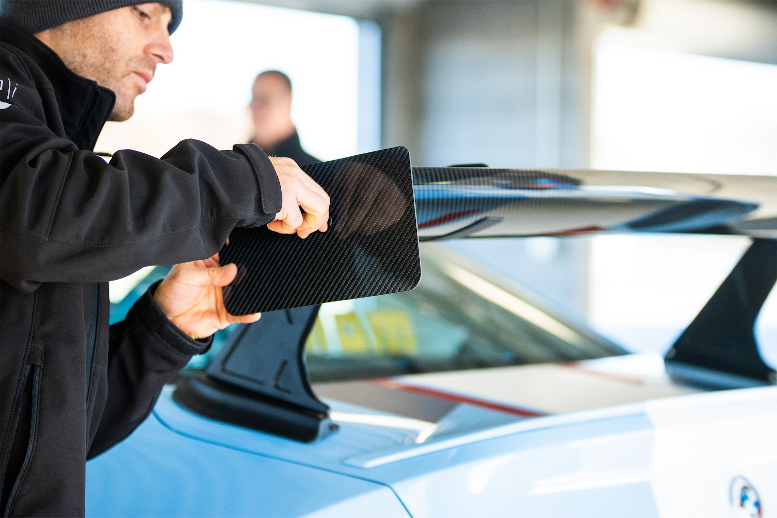 Man adjusting the swan neck rear wing on a BMW M2