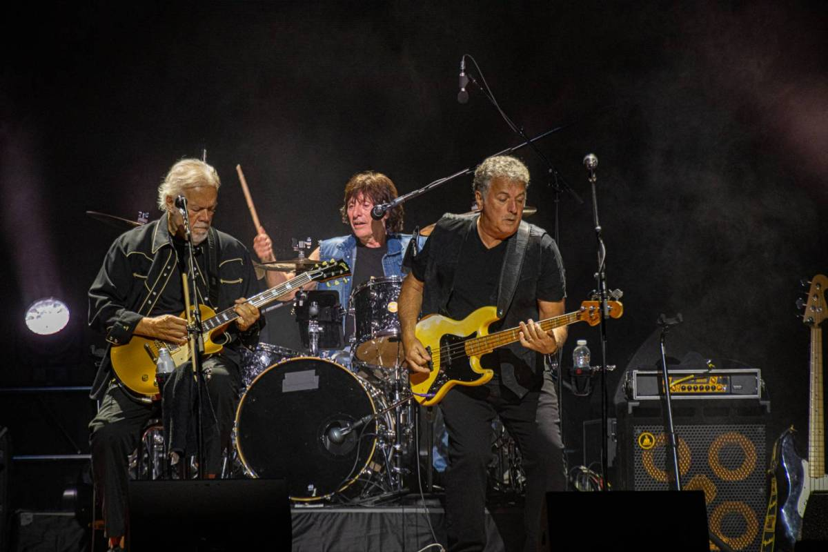 A live show of two guitarists and a drummer performing onstage as part of Bahman Turner Overdrive