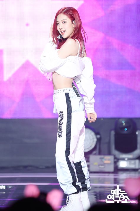 This contains an image of BLACKPINK Rosé  with red hair wearing white and black tracksuits while standing on stage