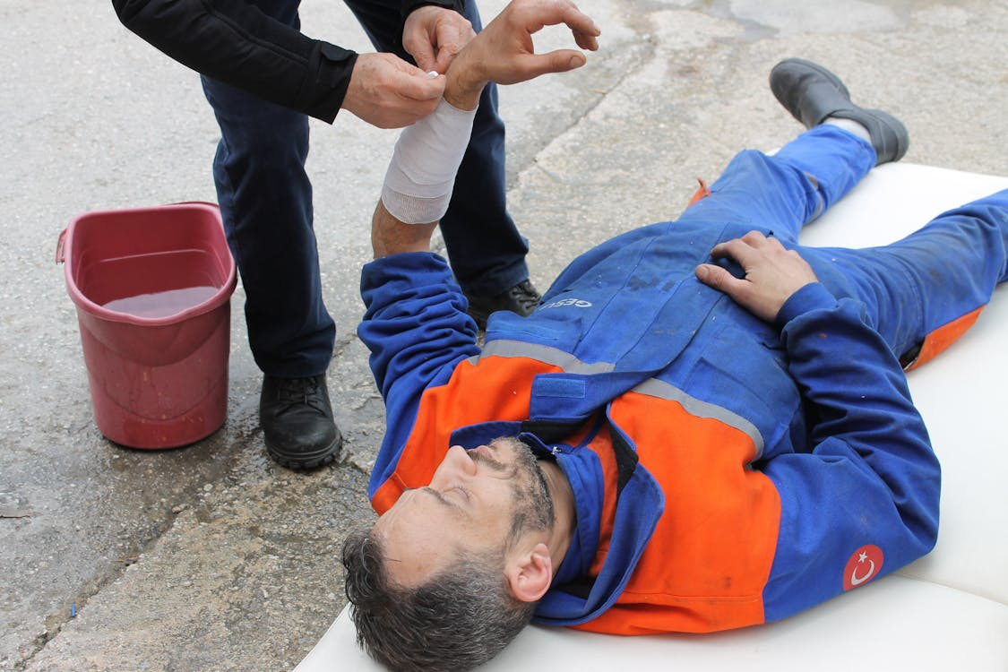 Injured worker receiving first aid on site, illustrating the importance of incident management systems in safety response.