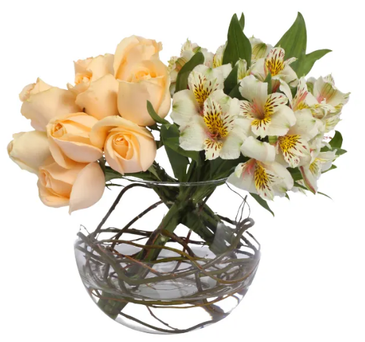 Arranjo de alstroemérias brancas com rosa e amarelo e rosas beges entrelaçadas em vaso tipo aguário com metade preenchida de água e fundo branco.