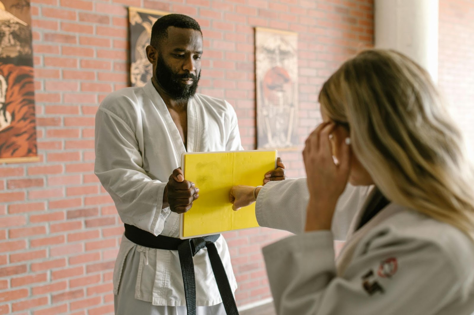 A martial arts student punching a paper held by an instructor