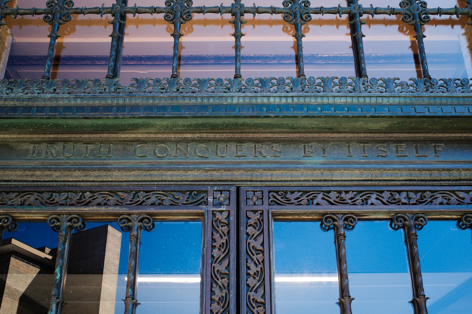 Copper etching above a doorway reading, “Truth Conquers By Itself.”
